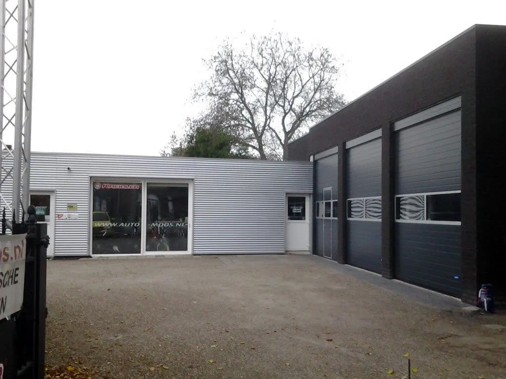 Het erf van Auto Moos met de winkel links en de werkplaats rechts