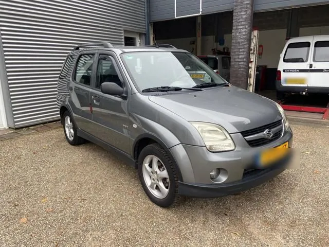 Grijze Suzuki Ignis voor de open werkplaatsdeuren van Auto Moos